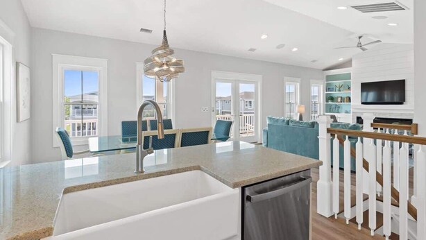 A modern kitchen with a built-in dishwasher, a dining area with a glass table, and a living room with a TV and seating. - Carlton by Brunswick Vacation Rentals: Private Pool, Elevator, and Beach Access (Supply)