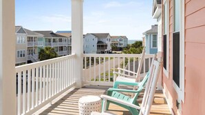 A covered porch with white railings, a small round table, and two turquoise chairs. - Carlton by Brunswick Vacation Rentals: Private Pool, Elevator, and Beach Access (Supply)