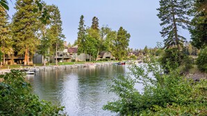 Vista de un lago con barcos amarrados, casas y árboles frondosos.