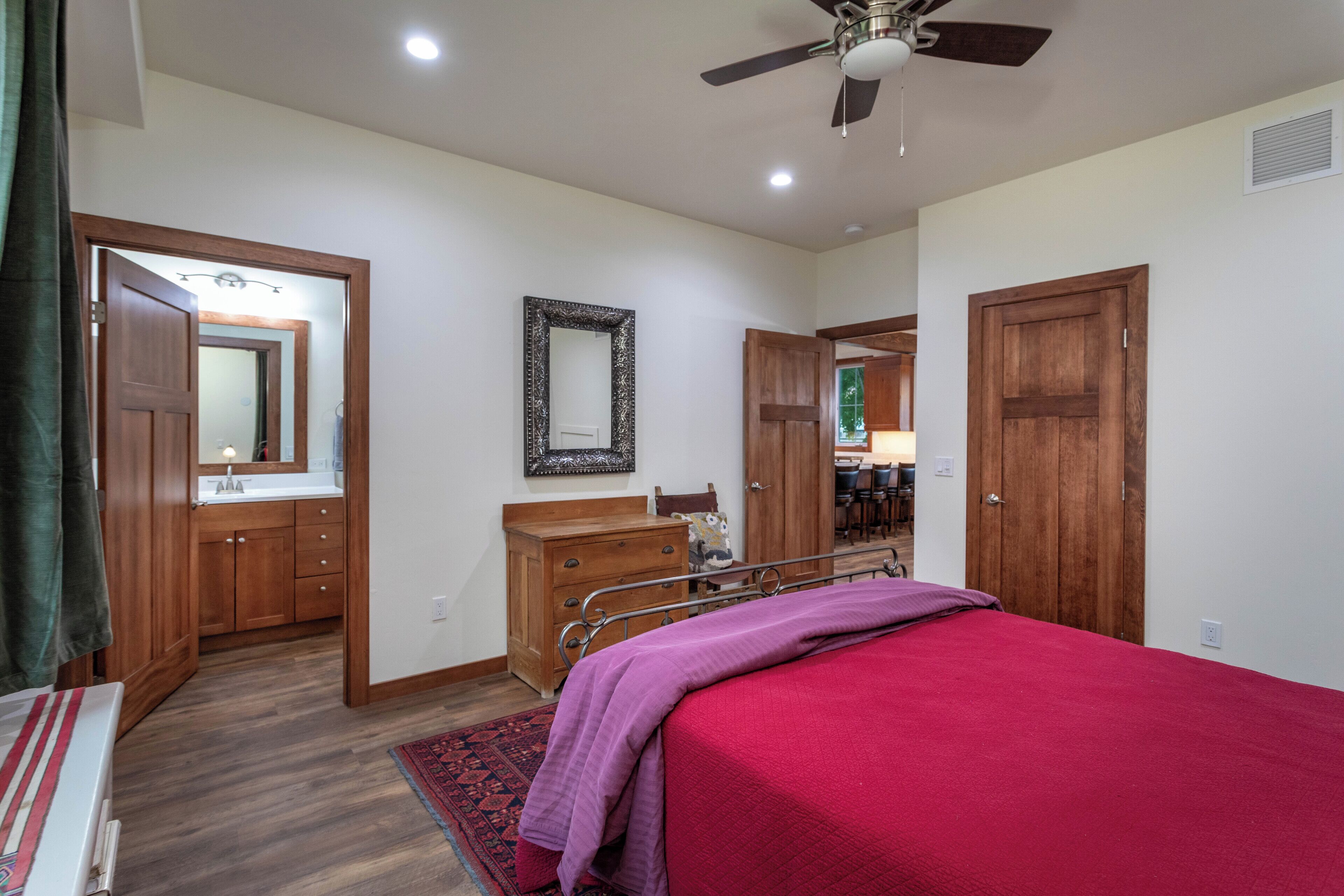 A bedroom with a bed, wooden wardrobe, mirror, and a ceiling fan.
