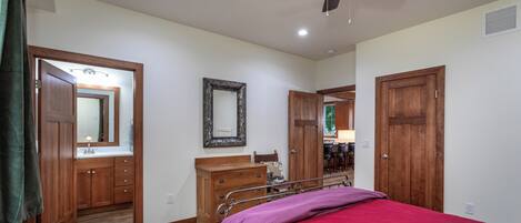 A bedroom with a bed, wooden wardrobe, mirror, and a ceiling fan.