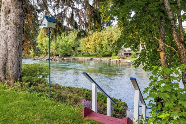 A riverside park with a wooden bench, a birdhouse, and a railing. - Shared Boat Dock, Waterfront Property, New build 2023 (Bigfork)