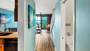 Un pasillo con una zona de cocina a la izquierda, un comedor en el centro y vistas al exterior a través de un ventanal.