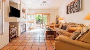 A living room with a sofa, coffee table, TV, fireplace, and a ceiling fan. - Relax in luxury at Sedona Desert Poppy, a 3-bed oasis in beautiful West Sedona. (Sedona)