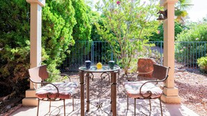 An outdoor patio with a round table and two chairs, surrounded by greenery and a metal fence. - Relax in luxury at Sedona Desert Poppy, a 3-bed oasis in beautiful West Sedona. (Sedona)