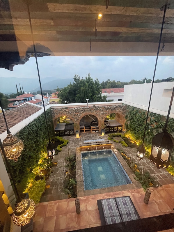 Un espace piscine aménagé sur le toit, agrémenté d’une arche en pierre, de sièges et de lanternes suspendues.