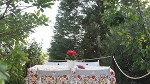 Eine Holzterrasse mit Tisch und zwei Stühlen, umgeben von Grünpflanzen.