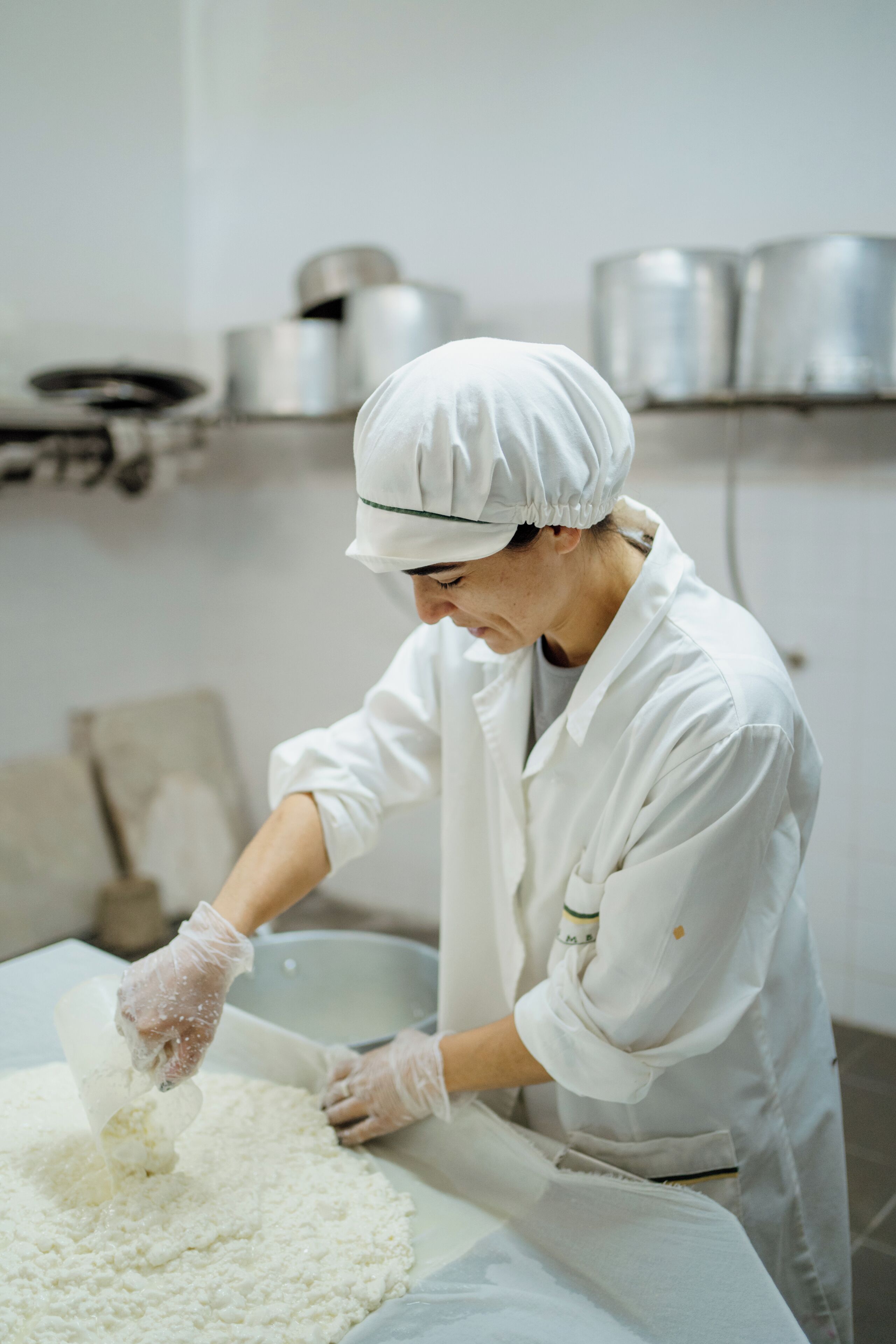 A person in a white uniform and hat working with a large container, likely in a kitchen or food preparation area.
