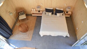 Ein gemütliches Schlafzimmer mit einem Bett, zwei Nachttischen, einem Sessel und einem kleinen Teppich.