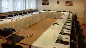 Ett konferensrum med ett långt bord, stolar och en projektor.