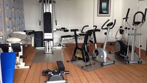 Ett gym med olika typer av träningsutrustning, inklusive löpband, motionscyklar och en roddmaskin.