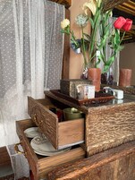 Un aparador de madera con un espejo encima, un jarrón con flores y una mesa con una bandeja y velas.