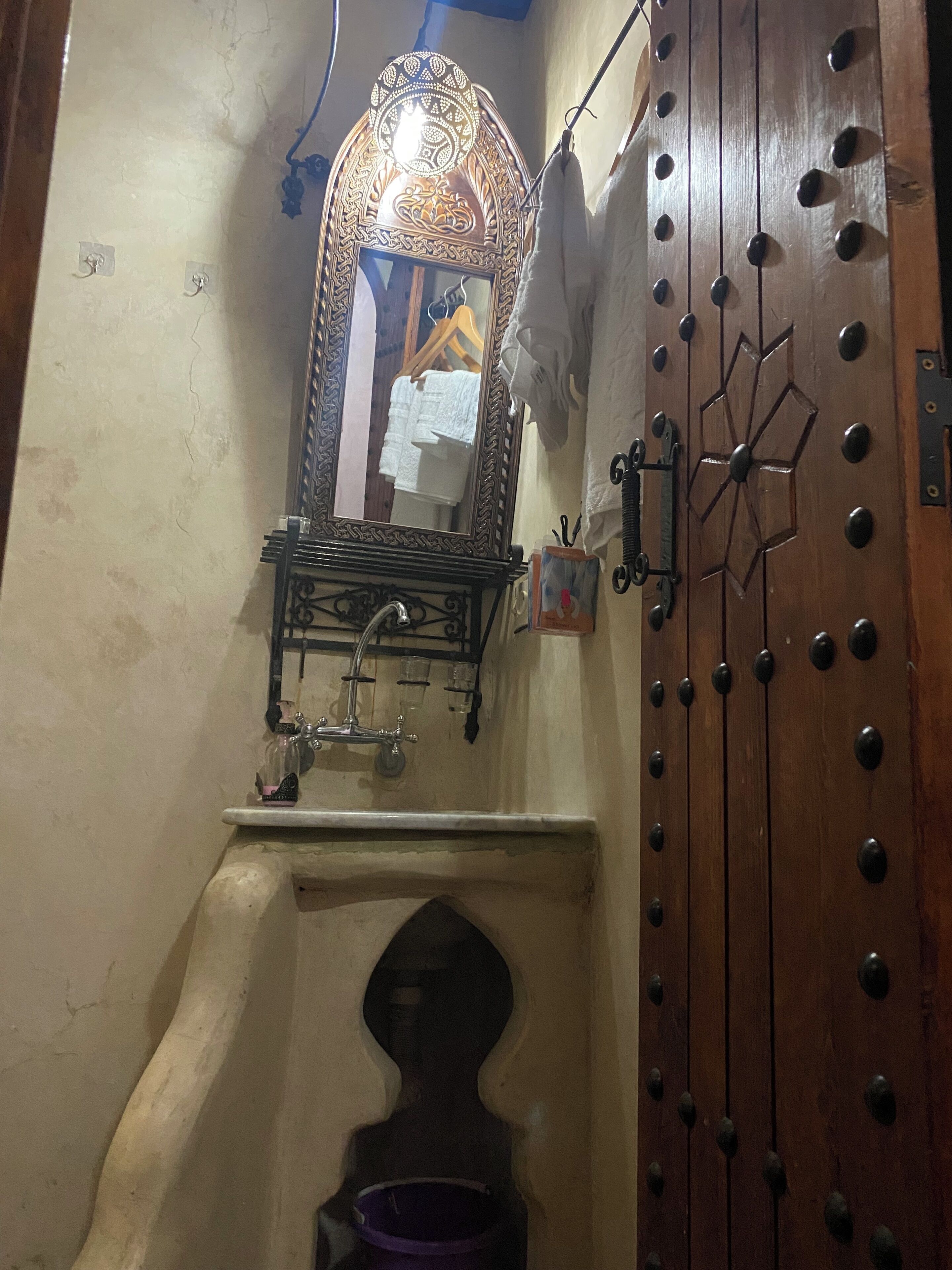 Un baño con puerta de madera, espejo y lavabo.