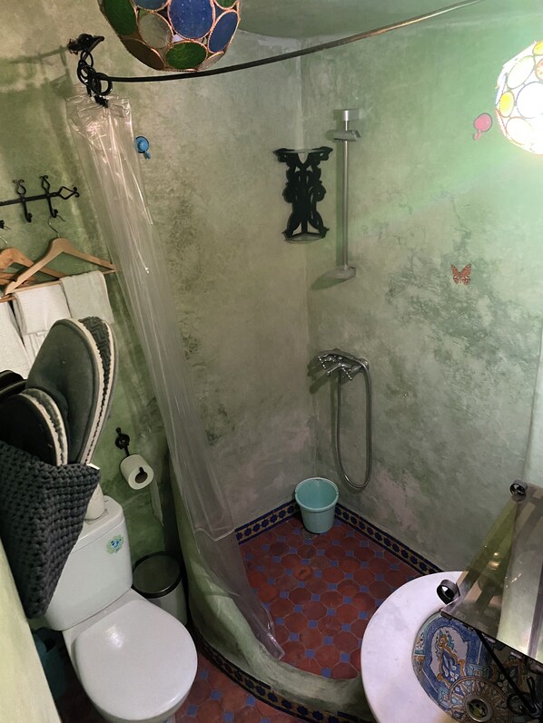 Un baño con ducha, dos inodoros y un lavamanos.