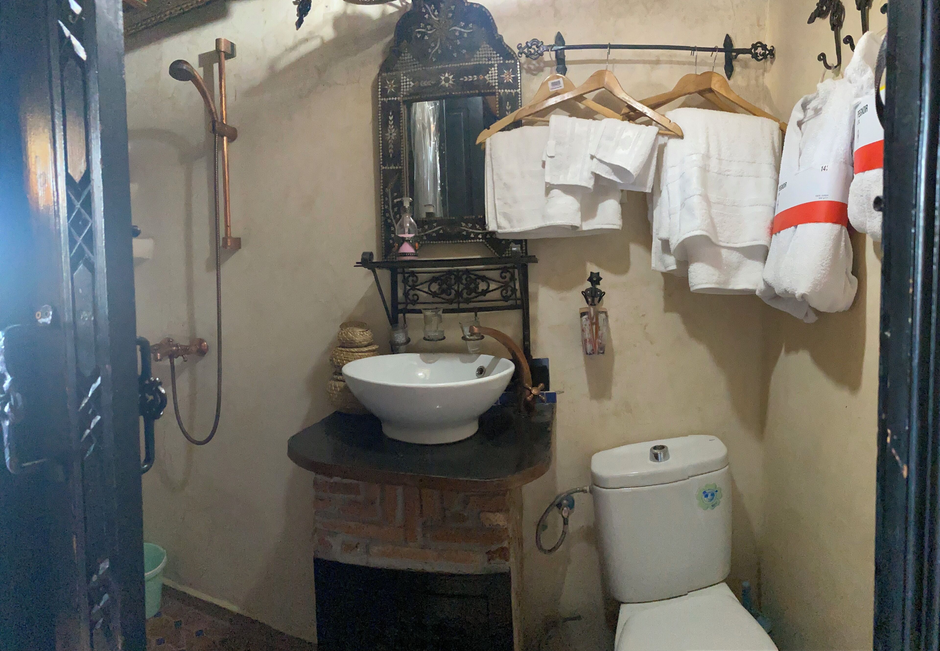 A bathroom with a white sink, a toilet, and a shower. There are towels hanging on a rack.