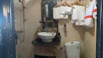 A bathroom with a white sink, a toilet, and a shower. There are towels hanging on a rack.