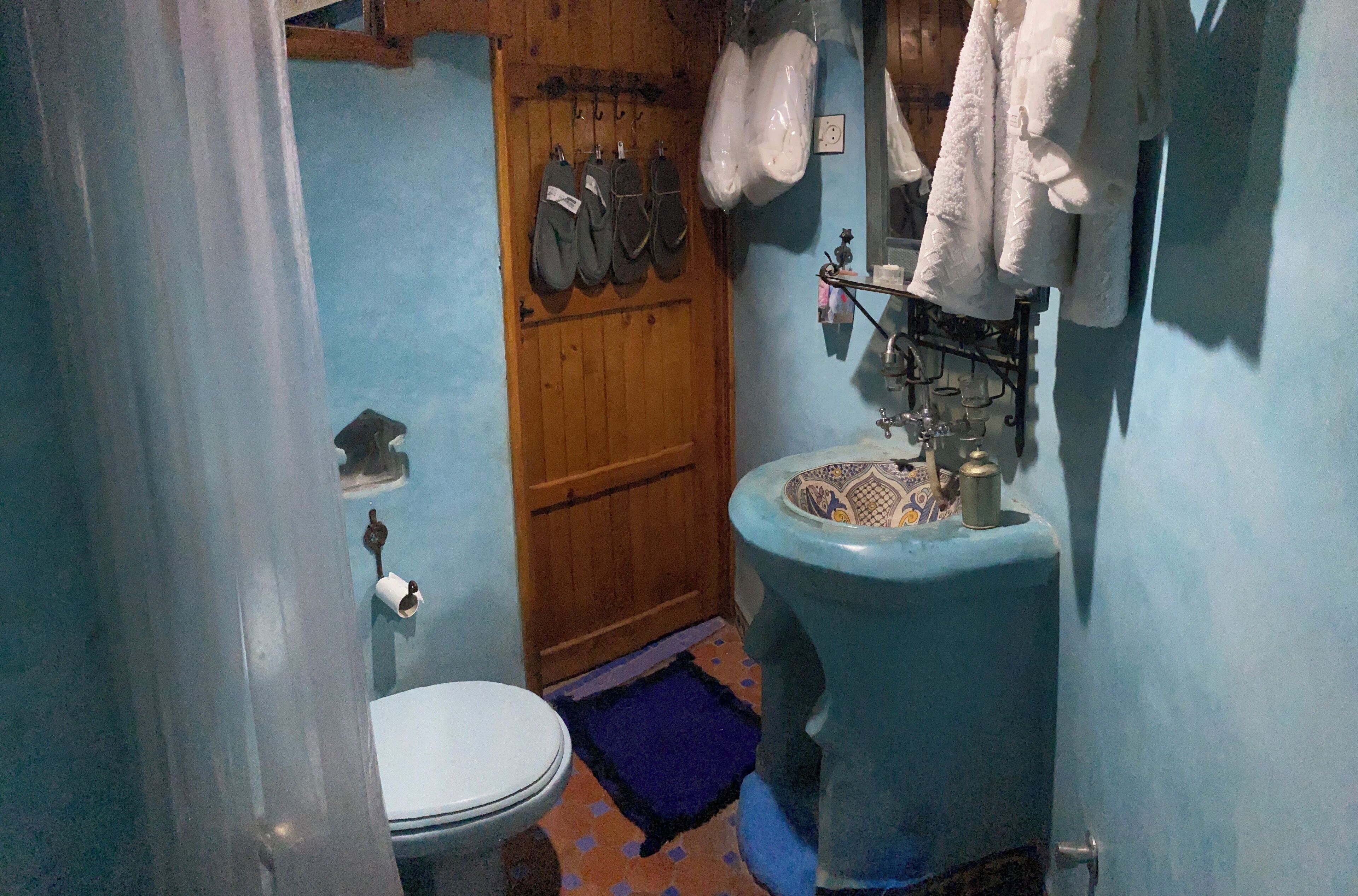 Une salle de bain comprenant des toilettes, un lavabo avec un receveur décoratif et un espace douche.