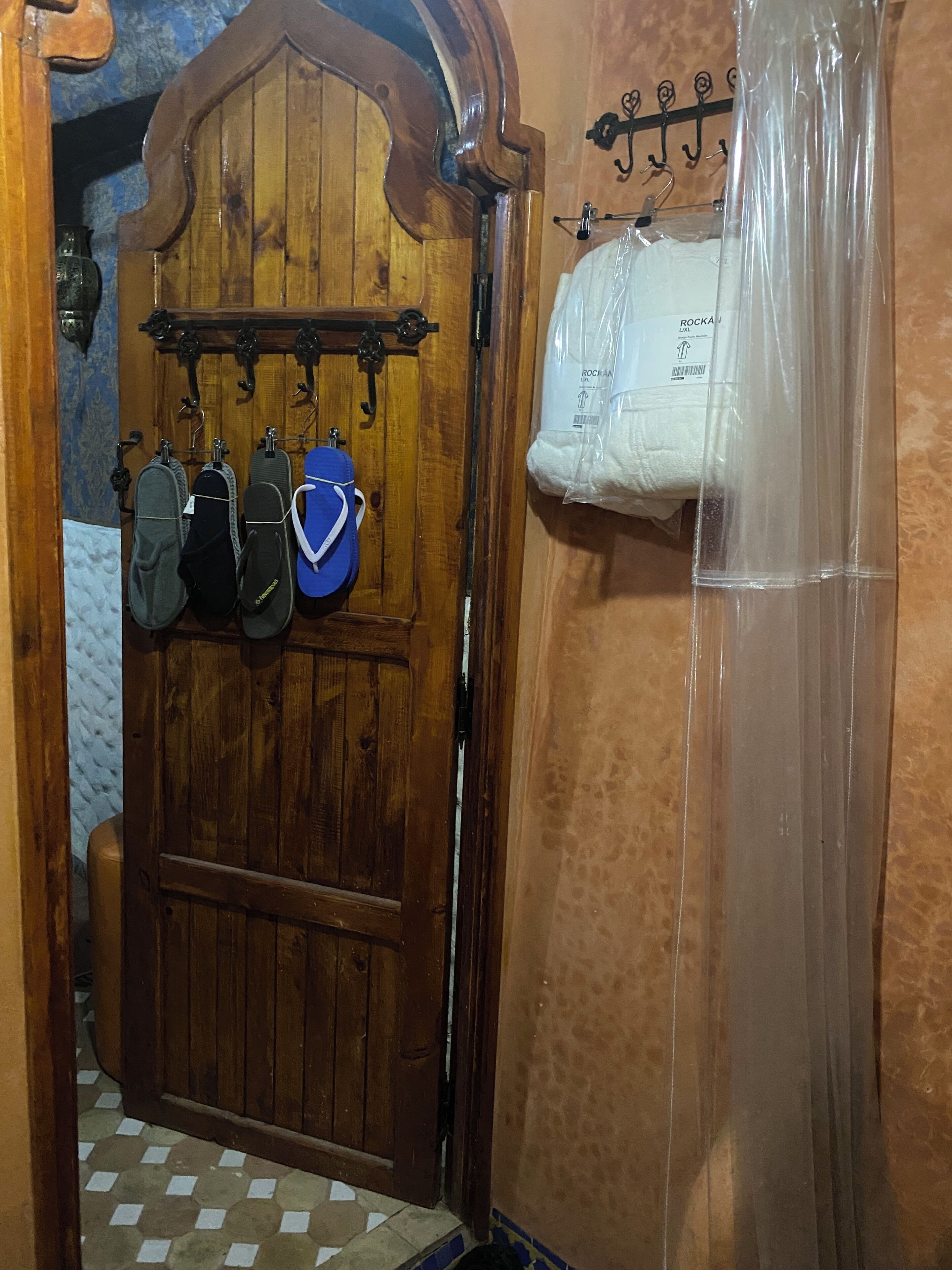Una puerta de madera con un perchero encima, donde hay varios pares de zapatos.