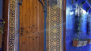 A wooden door with intricate metalwork and a patterned wall. - Riad Azurite (Chefchaouen)