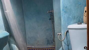 A bathroom with a shower, toilet, and blue-tiled floor.