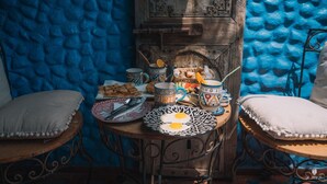 A rustic dining area with a wooden table set for breakfast, featuring bread, eggs, and a variety of mugs and plates. - Riad Azurite (Chefchaouen)