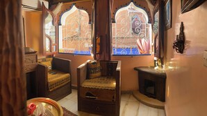 A traditional room with a wooden sofa, a small wooden cabinet, and a decorative wall shelf. - Riad Azurite (Chefchaouen)