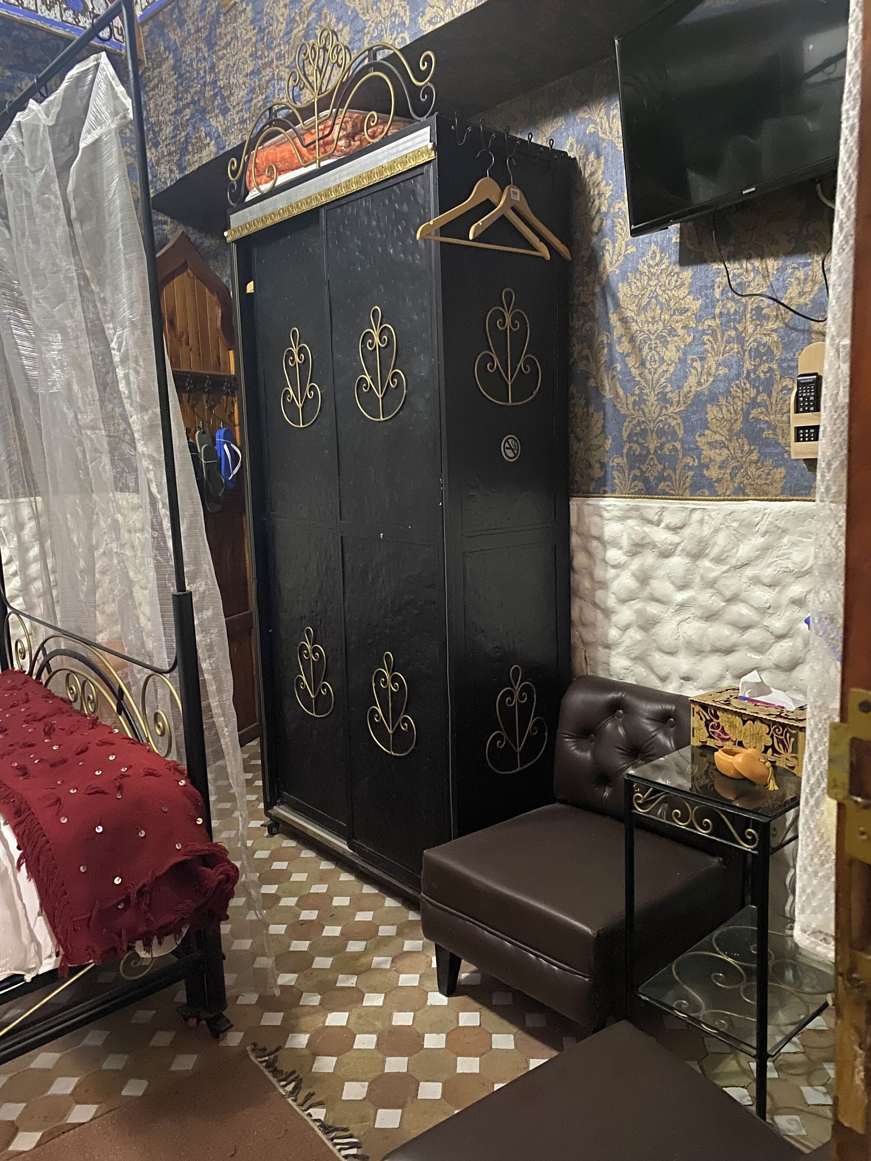 Ein Schlafzimmer mit einem Bett, einem Kleiderschrank, einem Fernseher und einem kleinen Tisch mit einer Schachtel.
