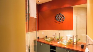 Une salle de bain moderne dotée d’une douche à parois de verre, d’un grand miroir et d’une décoration murale originale représentant des poissons.