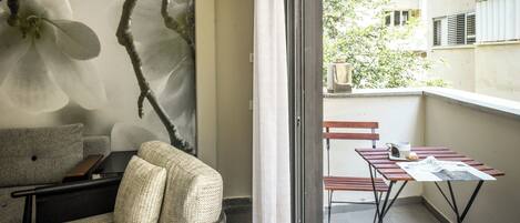 A balcony with a table, chairs, and a sofa.