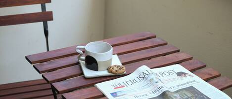A wooden bench with a newspaper, a mug, and a cookie.