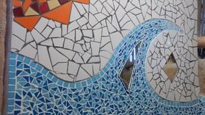 Un mur en mosaïque orné d’un motif ondulé et de petits galets en bas.