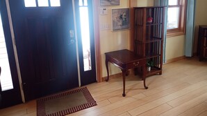 A room with a wooden floor, a dark door, a small table, and a bookshelf.