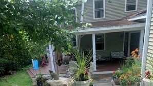 A garden with potted plants, a stone pathway, and a house with a porch.