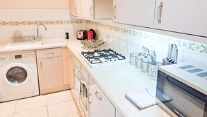 Une cuisine compacte équipée d’un lave-linge, d’une cuisinière à gaz et d’un four à micro-ondes.