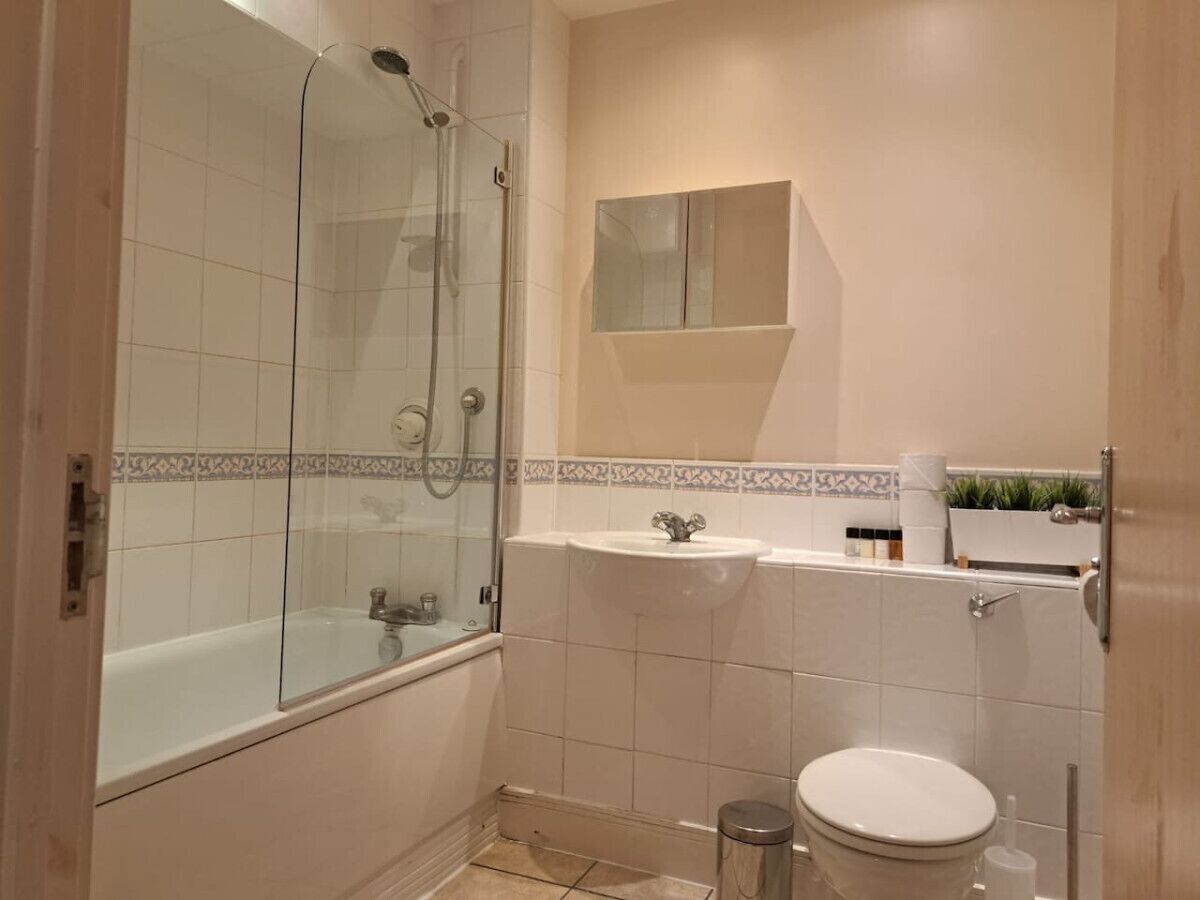 A bathroom with a glass-enclosed shower, a sink, and a toilet.