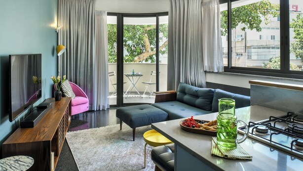 A modern living room with a sofa, ottoman, and a dining area with a table and chairs. - Turquoise Chic Dizengoff CTR by SeaNRent (Tel Aviv)