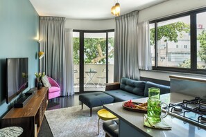 A modern living room with a sofa, ottoman, and a dining area with a table and chairs. - Turquoise Chic Dizengoff CTR by SeaNRent (Tel Aviv)