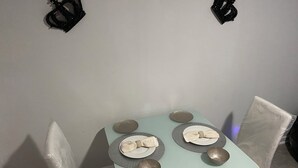 Ein kleiner Esstisch mit zwei Stühlen, einem Wandbehang und einer hellblauen Tischdecke.