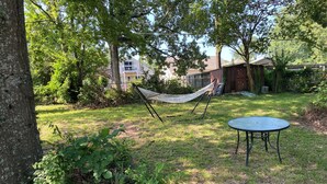 Eine grüne Rasenfläche mit einer Hängematte und einem runden Tisch.
