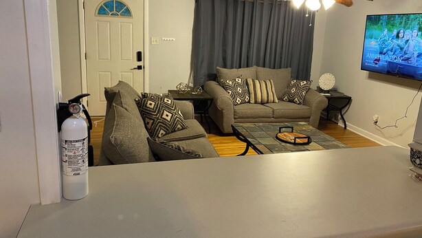 Ein Wohnzimmer mit einer Couch, einem Couchtisch, einem Fernseher und einem Deckenventilator.