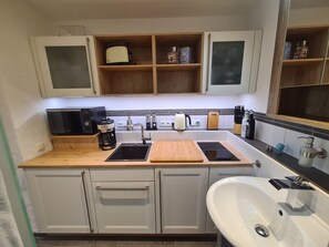 A modern kitchen with a built-in microwave, coffee maker, toaster, and a sink with a soap dispenser.
