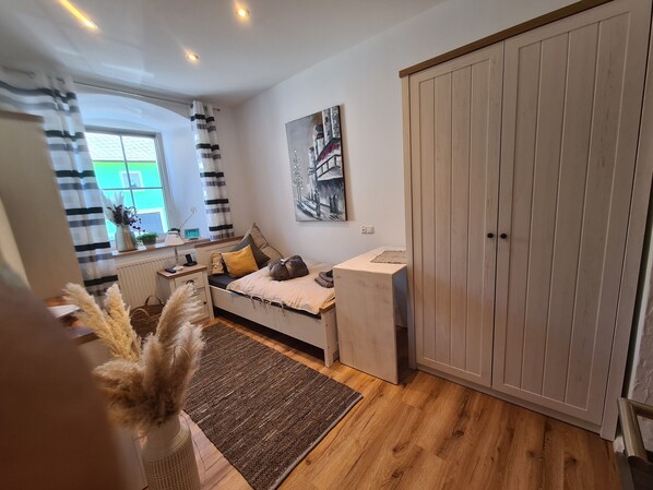 A bedroom with a bed, bedside table, lamp, and a large wardrobe.