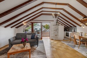 Un espace de vie de style loft avec un plafond haut, des poutres en bois, un canapé, une table à manger et un coin cuisine.