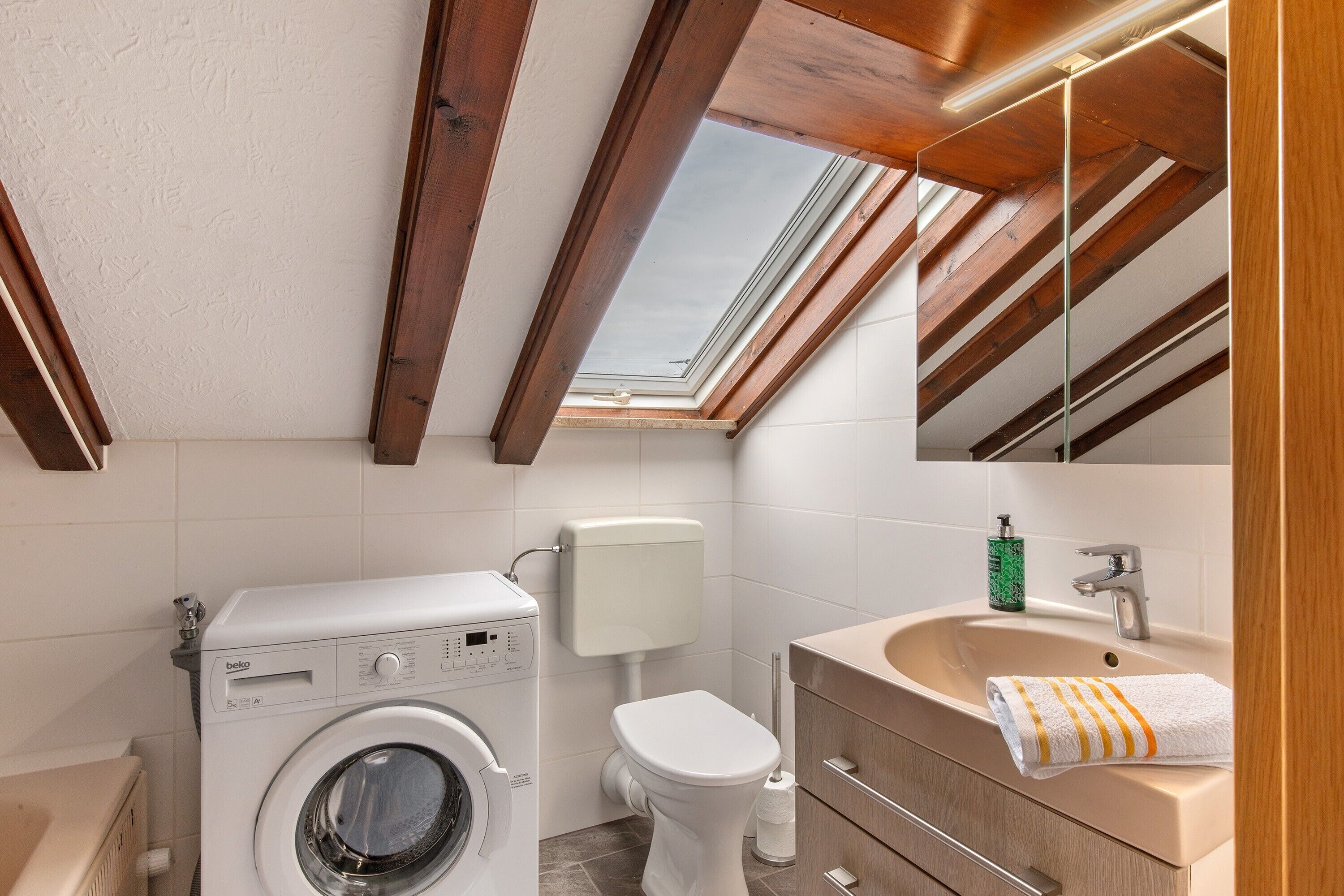 Un baño pequeño con lavadora, inodoro y lavamanos.