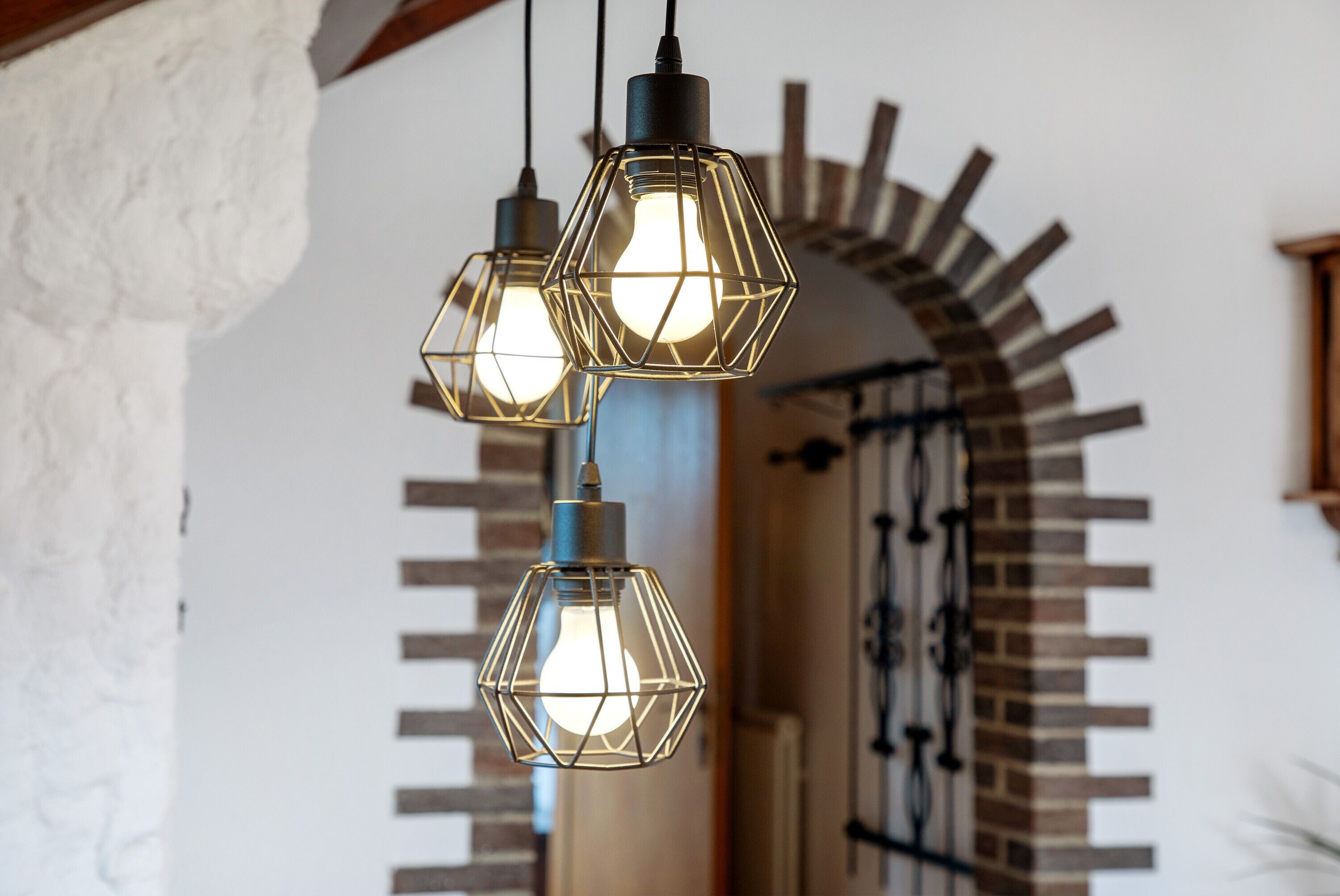 A set of three hexagonal pendant lights with exposed bulbs, hanging from a ceiling.