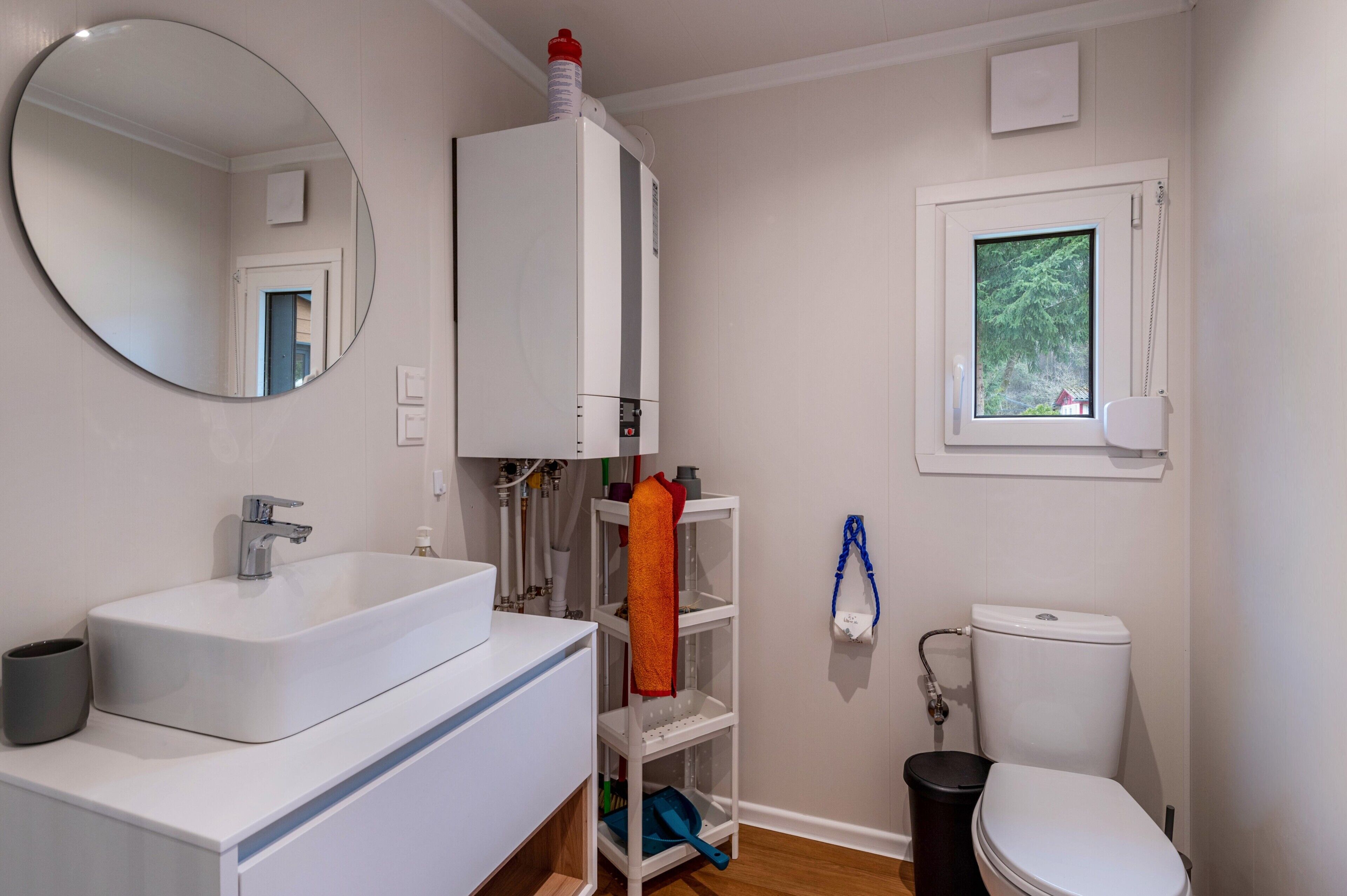 Ein Badezimmer mit weißem Waschbecken, Spiegel, Toilette und Fenster.