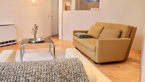 Een moderne woonkamer met een bank, een salontafel en een kleine plant.