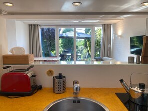 Eine moderne Küche mit Spüle, Toaster, Wasserkocher und einem Fenster mit Blick ins Freie.
