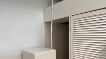 Une pièce avec une armoire blanche, un banc blanc et une fenêtre avec des stores.