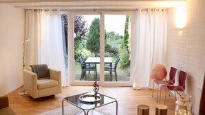 Een moderne woonkamer met een glazen tafel, een bank en een zithoek met stoelen.